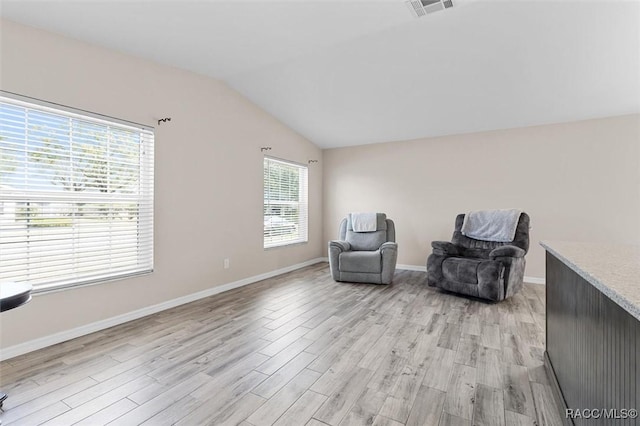 living area featuring vaulted ceiling and light hardwood / wood-style floors