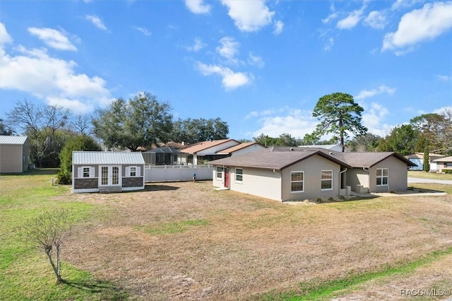 back of house with an outbuilding, a lawn, and french doors