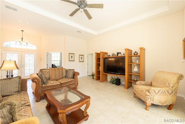 living room with visible vents, a raised ceiling, a high ceiling, french doors, and ceiling fan with notable chandelier