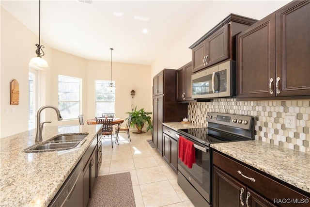 kitchen with appliances with stainless steel finishes, a sink, dark brown cabinetry, and tasteful backsplash