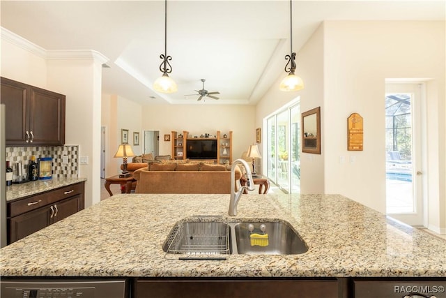 kitchen with backsplash, dark brown cabinets, a sink, and open floor plan