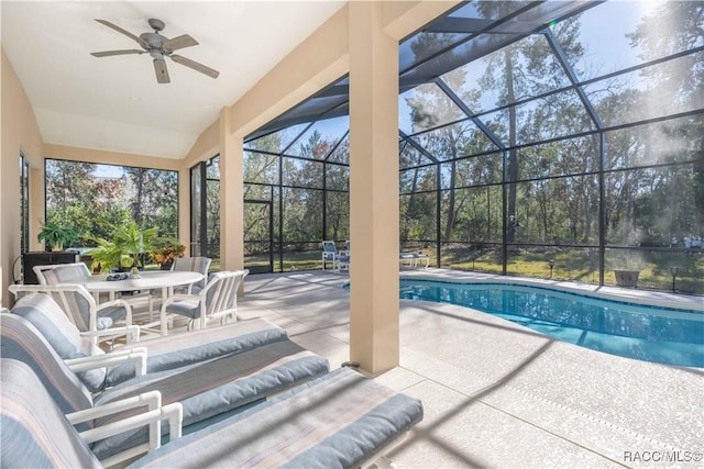 outdoor pool featuring outdoor dining space, glass enclosure, a patio area, and ceiling fan