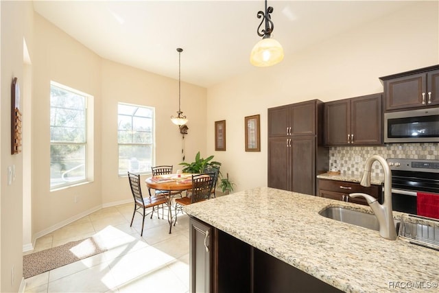 kitchen featuring tasteful backsplash, pendant lighting, stainless steel microwave, and dark brown cabinets