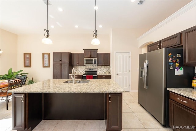 kitchen featuring appliances with stainless steel finishes, hanging light fixtures, a sink, dark brown cabinets, and backsplash