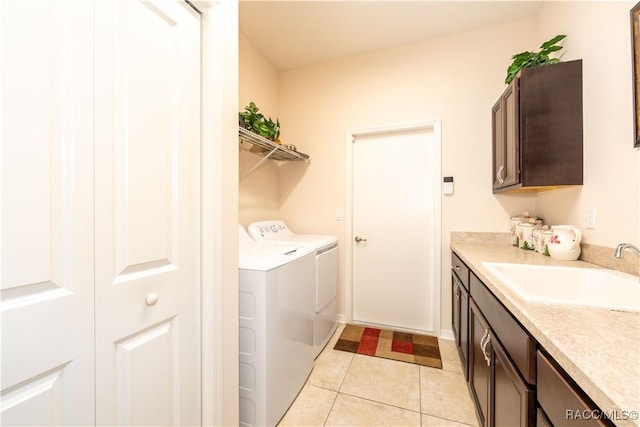 washroom with light tile patterned floors, washing machine and dryer, a sink, and cabinet space