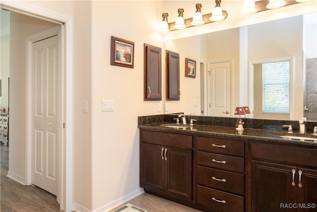 bathroom with a sink, baseboards, and double vanity