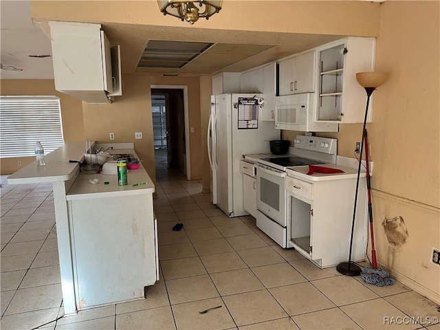 kitchen with light tile patterned floors, white appliances, white cabinetry, and sink