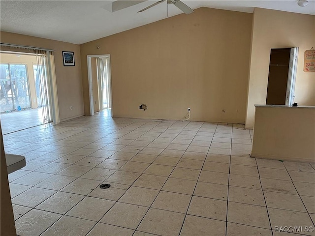 tiled empty room with a textured ceiling, ceiling fan, and lofted ceiling