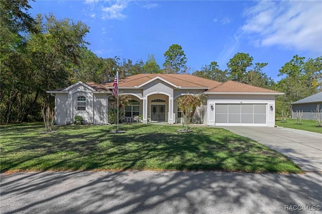 mediterranean / spanish-style house with driveway, a front lawn, an attached garage, and stucco siding