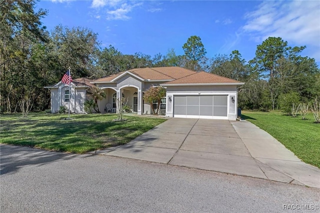 view of front facade with driveway, an attached garage, a front lawn, and stucco siding