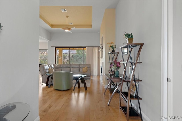 living room with a raised ceiling and light hardwood / wood-style flooring