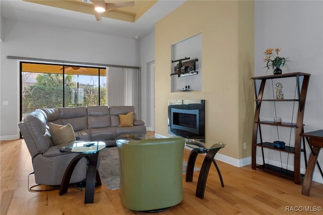 living room with light hardwood / wood-style flooring, ceiling fan, and a high ceiling