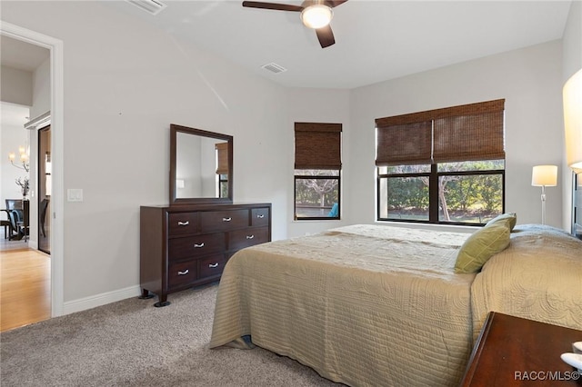 bedroom with ceiling fan with notable chandelier and light carpet