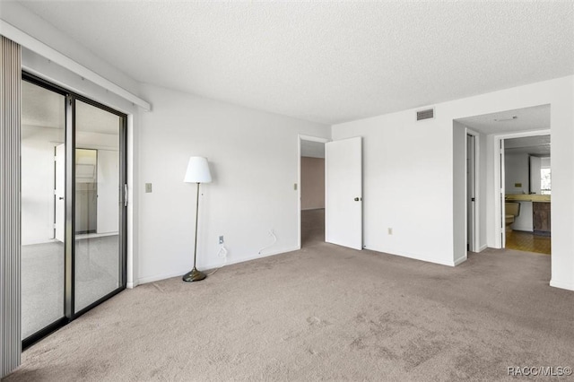 unfurnished bedroom featuring light colored carpet and a textured ceiling