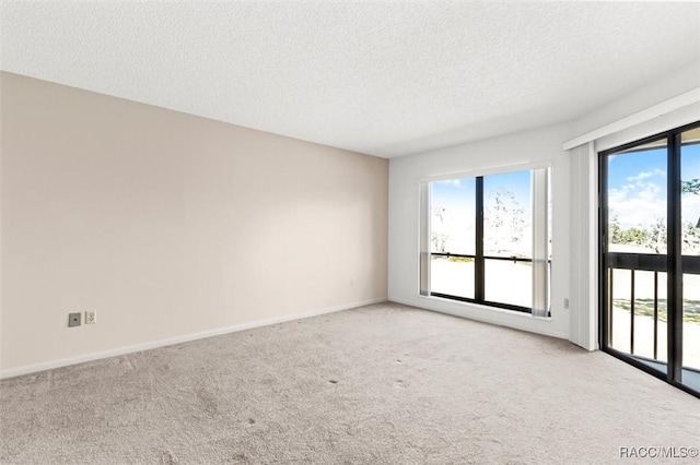 carpeted spare room featuring plenty of natural light and a textured ceiling