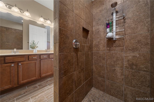 bathroom featuring vanity, wood-type flooring, and a tile shower