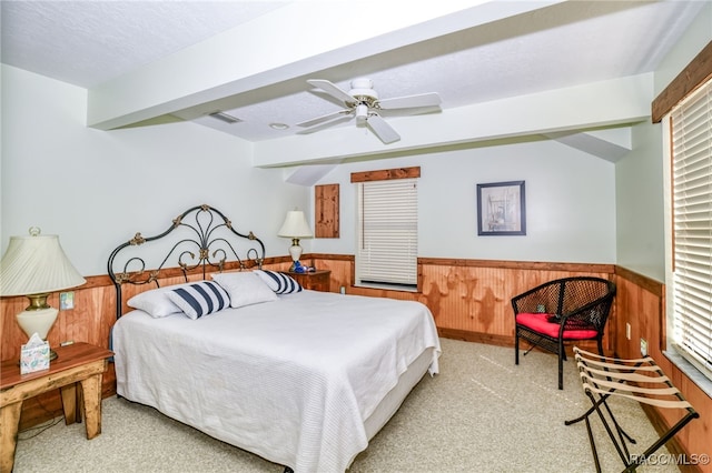 bedroom with a wainscoted wall, carpet floors, wood walls, visible vents, and beam ceiling