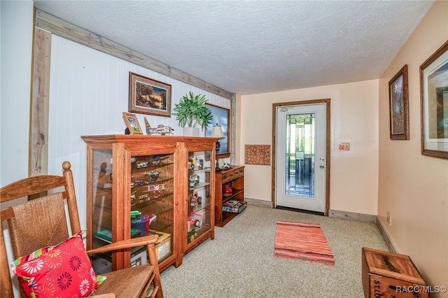 carpeted entrance foyer featuring a textured ceiling and baseboards