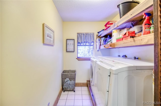 laundry room with laundry area, baseboards, washing machine and clothes dryer, a textured ceiling, and light tile patterned flooring