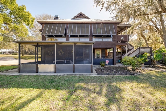 back of house with stairs, a lawn, a chimney, and a sunroom