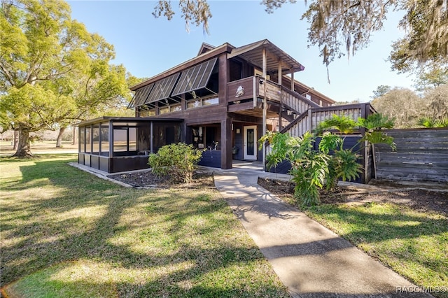 view of front of house featuring a deck, a front lawn, stairway, and a sunroom