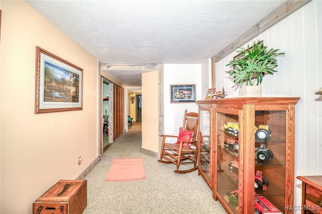 corridor featuring baseboards, a textured ceiling, and carpet flooring