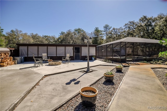 view of patio with a fire pit, glass enclosure, and a swimming pool