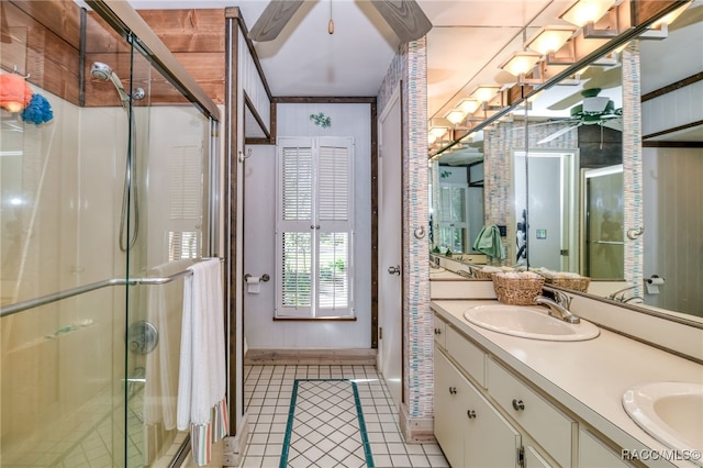 full bathroom with double vanity, a ceiling fan, tile patterned flooring, a shower stall, and a sink