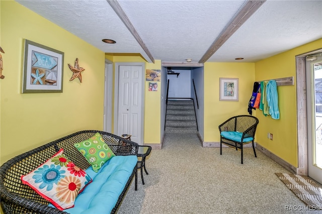 sitting room featuring a textured ceiling, carpet floors, stairway, and baseboards