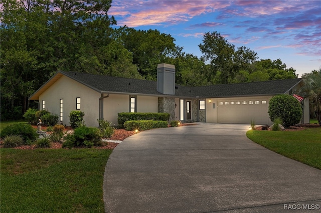 ranch-style home featuring a garage and a lawn