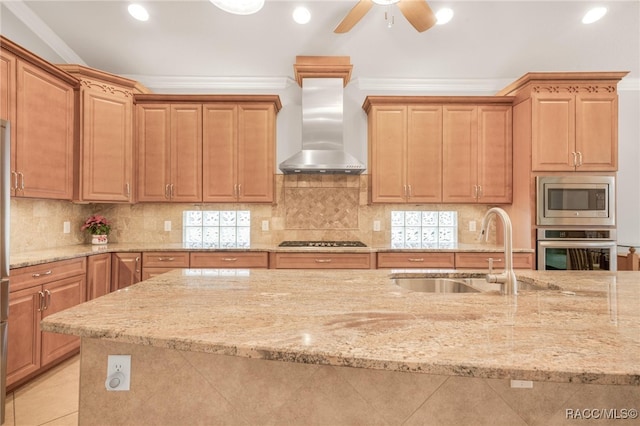 kitchen featuring stainless steel appliances, ornamental molding, light stone counters, wall chimney exhaust hood, and sink