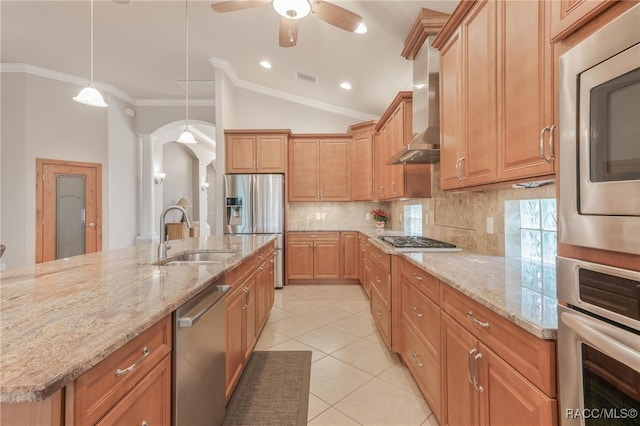 kitchen with sink, stainless steel appliances, wall chimney exhaust hood, decorative backsplash, and pendant lighting