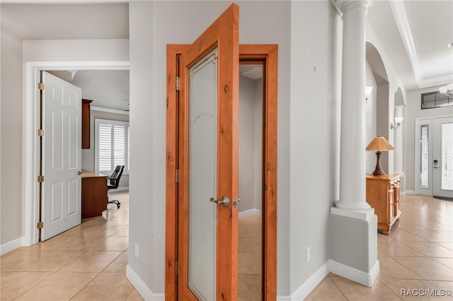 hall with ornamental molding, light tile patterned floors, and decorative columns