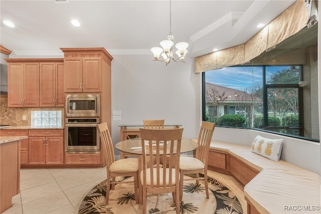 kitchen with pendant lighting, an inviting chandelier, breakfast area, appliances with stainless steel finishes, and ornamental molding