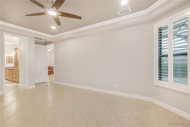 tiled empty room with ceiling fan, crown molding, and a raised ceiling