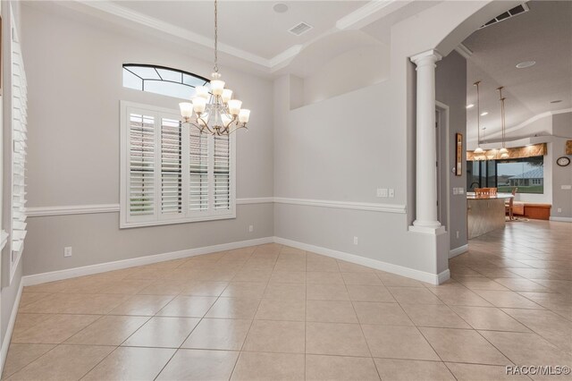 spare room with a wealth of natural light, an inviting chandelier, light tile patterned flooring, and ornate columns