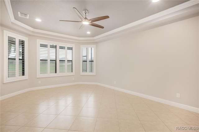 tiled empty room with ornamental molding, ceiling fan, and a tray ceiling