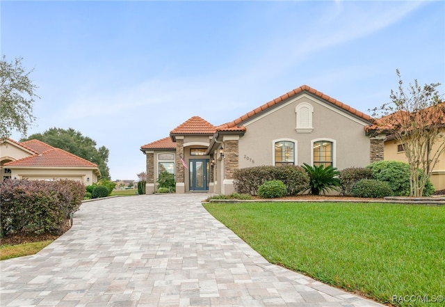 mediterranean / spanish-style house featuring a front yard and a garage