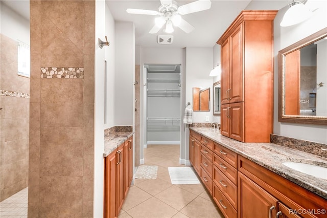 bathroom with ceiling fan, vanity, a tile shower, and tile patterned floors