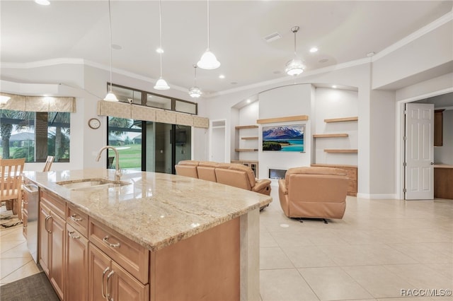 kitchen featuring light stone counters, decorative light fixtures, a center island with sink, built in features, and sink