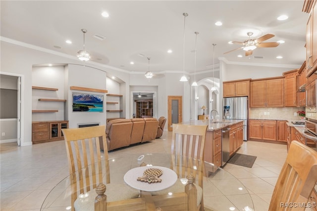 tiled dining space with sink, lofted ceiling, ceiling fan, and crown molding