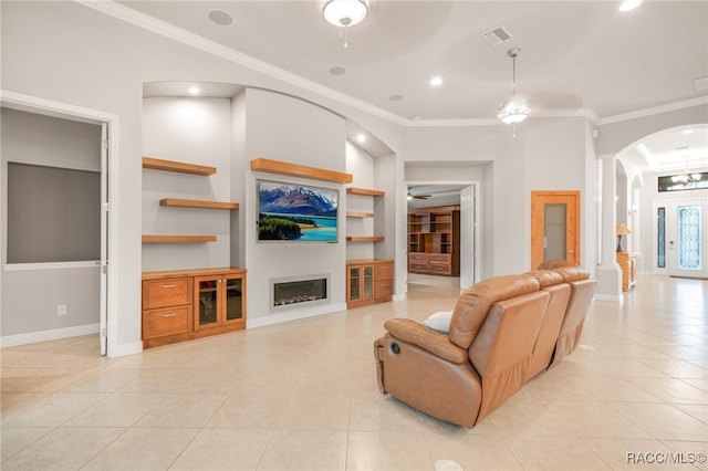 living room featuring built in shelves, light tile patterned floors, ceiling fan, and crown molding