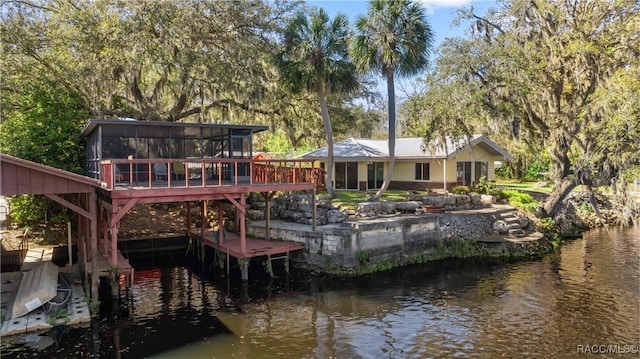 rear view of property featuring a deck with water view and a sunroom