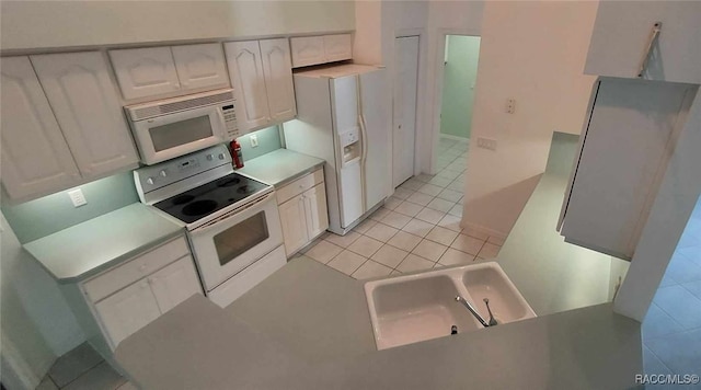 kitchen with light countertops, a sink, light tile patterned floors, white appliances, and white cabinetry