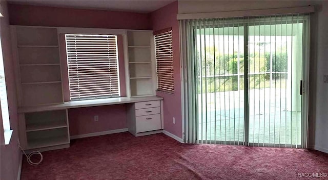unfurnished office with built in desk, carpet, and baseboards