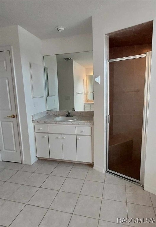 full bath featuring baseboards, a shower stall, tile patterned flooring, and vanity