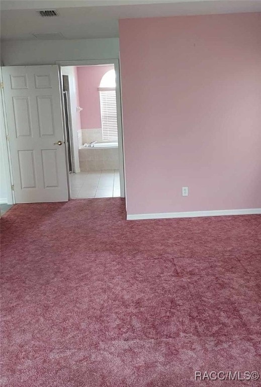 empty room featuring carpet floors, visible vents, and baseboards