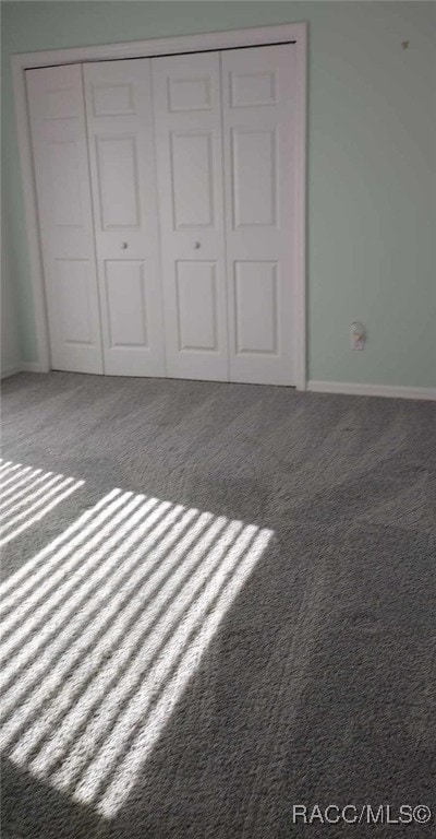 unfurnished bedroom with baseboards, carpet floors, and a closet