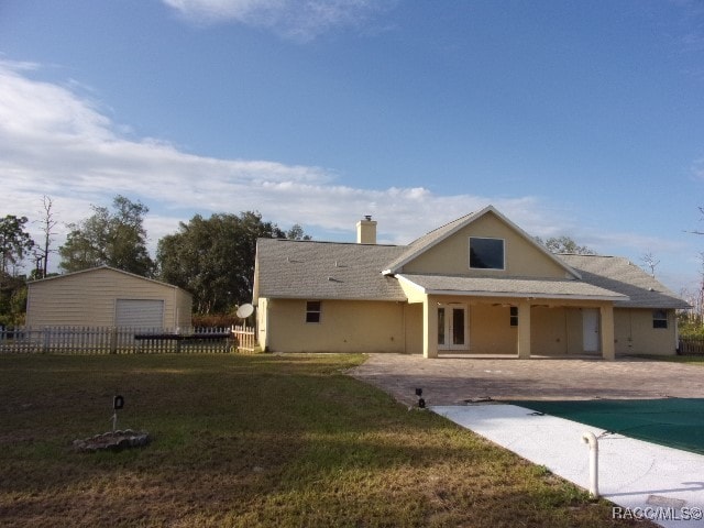 back of property featuring a lawn, a patio, and a covered pool