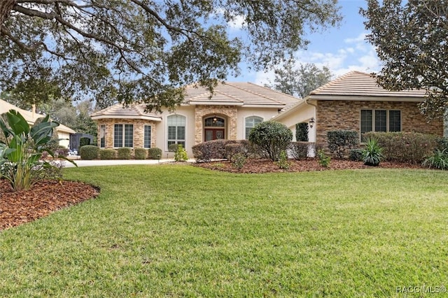 view of front of house featuring stone siding, a front lawn, and a tile roof